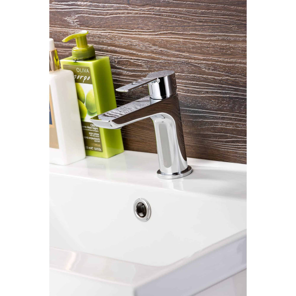 Shiny chrome bathroom tap with wooden panel background, next to soap and lotion bottles, showcasing modern bathroom fixtures and accessories.