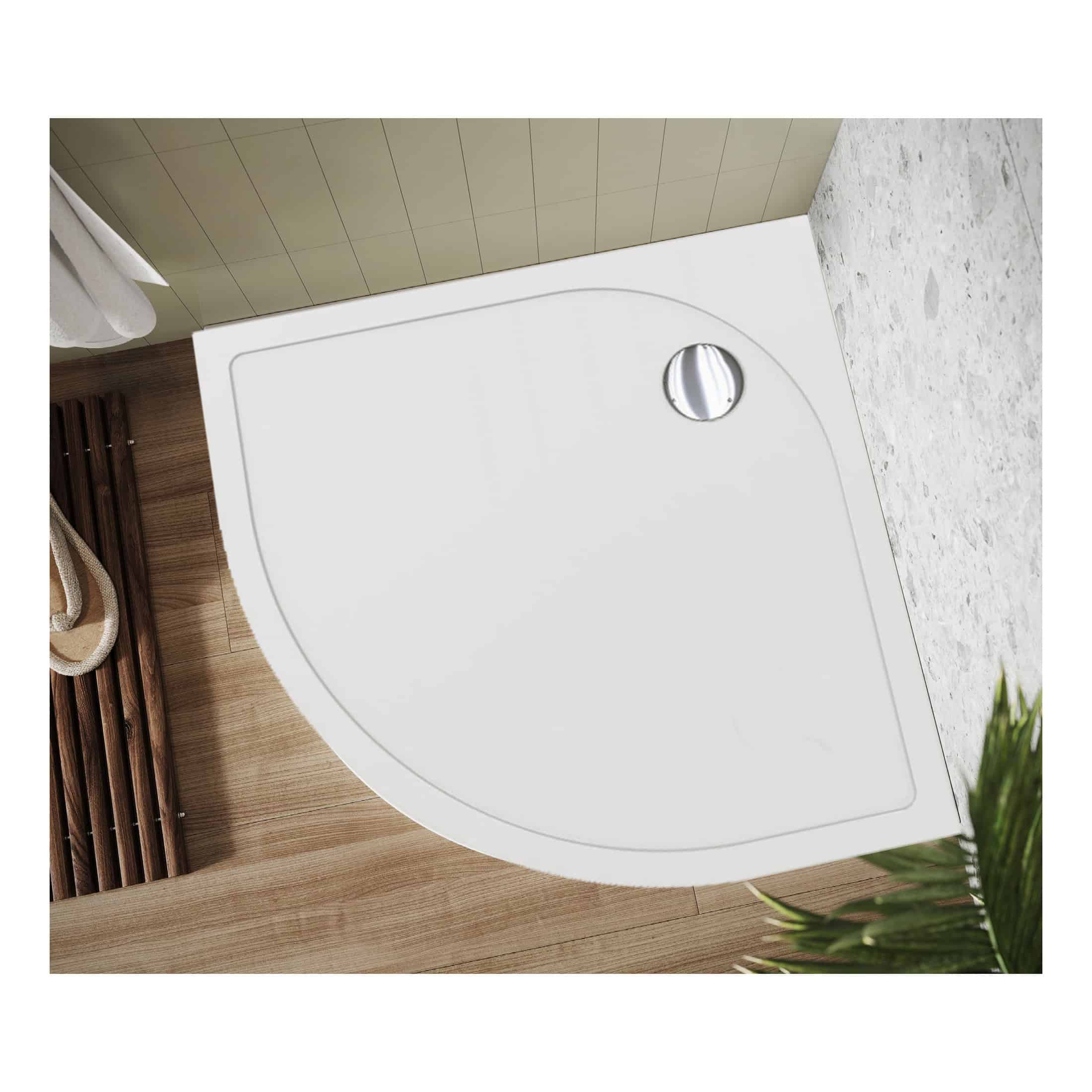 Sleek white quadrant shower tray with chrome drain, installed in a modern bathroom setting with wooden and tiled flooring. Ideal for contemporary bathroom designs and space-saving shower solutions.