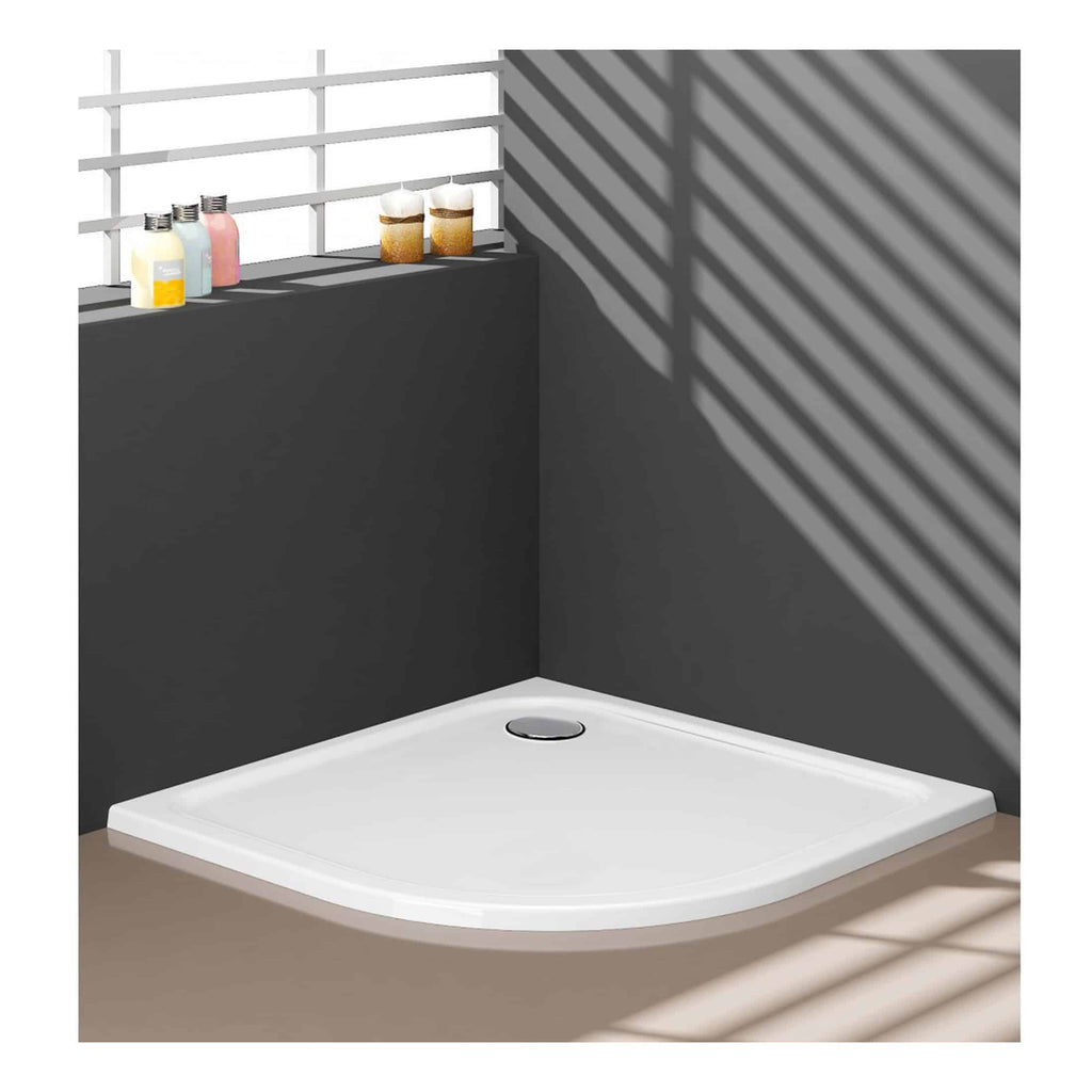 Modern shower base with sleek white finish and stainless steel drain, set against dark grey wall with decorative bottles and natural light pattern, ideal for contemporary bathroom upgrades.