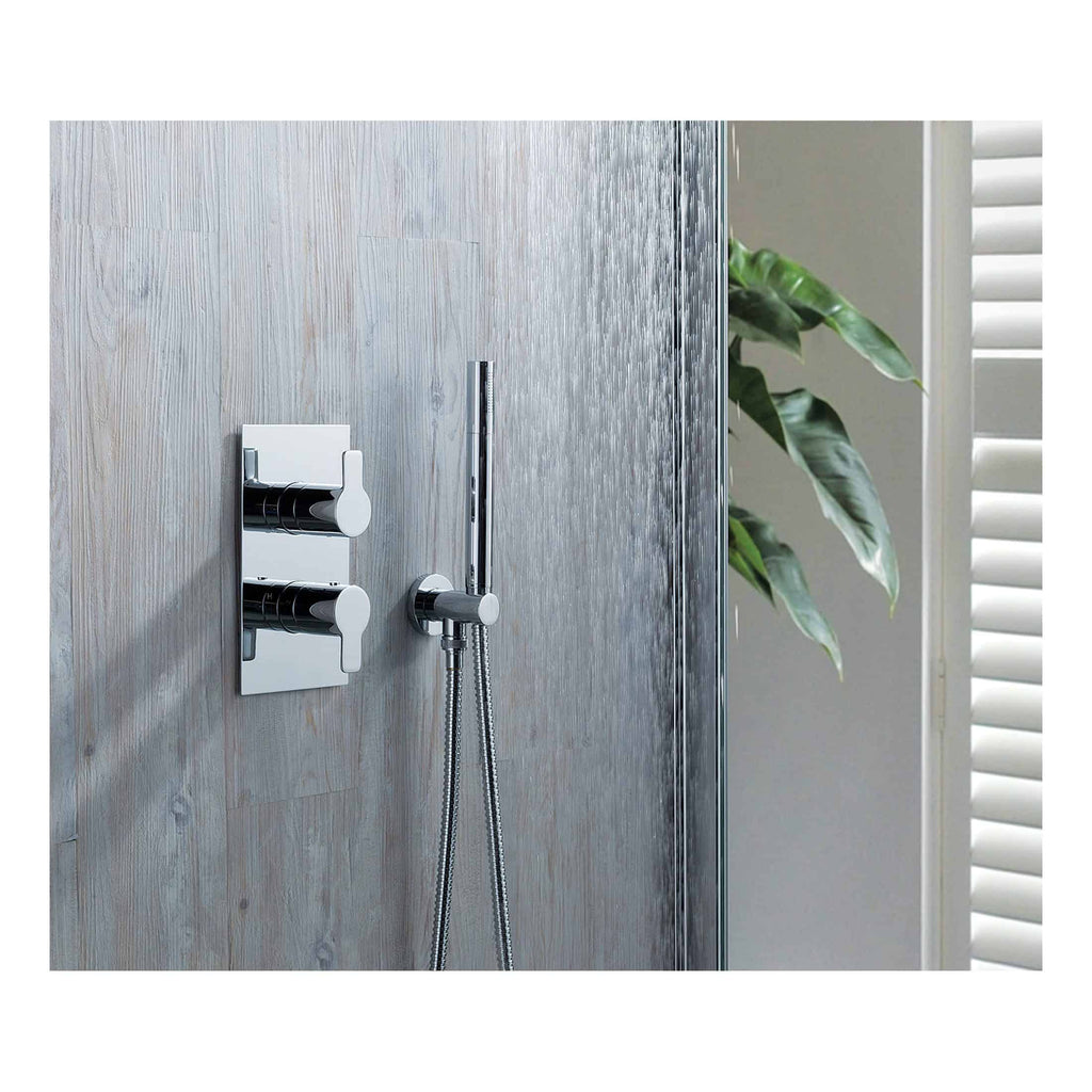 Sleek modern chrome bathroom shower mixer with handheld shower head, mounted on stylish textured wall with a green plant and white shutters in the background.
