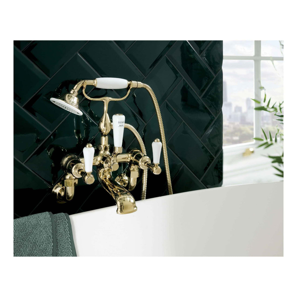 Elegant gold vintage-style bathroom tap with handheld shower and porcelain handles against a dark tile wall. Perfect for luxurious, high-end bathroom designs focused on classic aesthetics and premium fixtures.