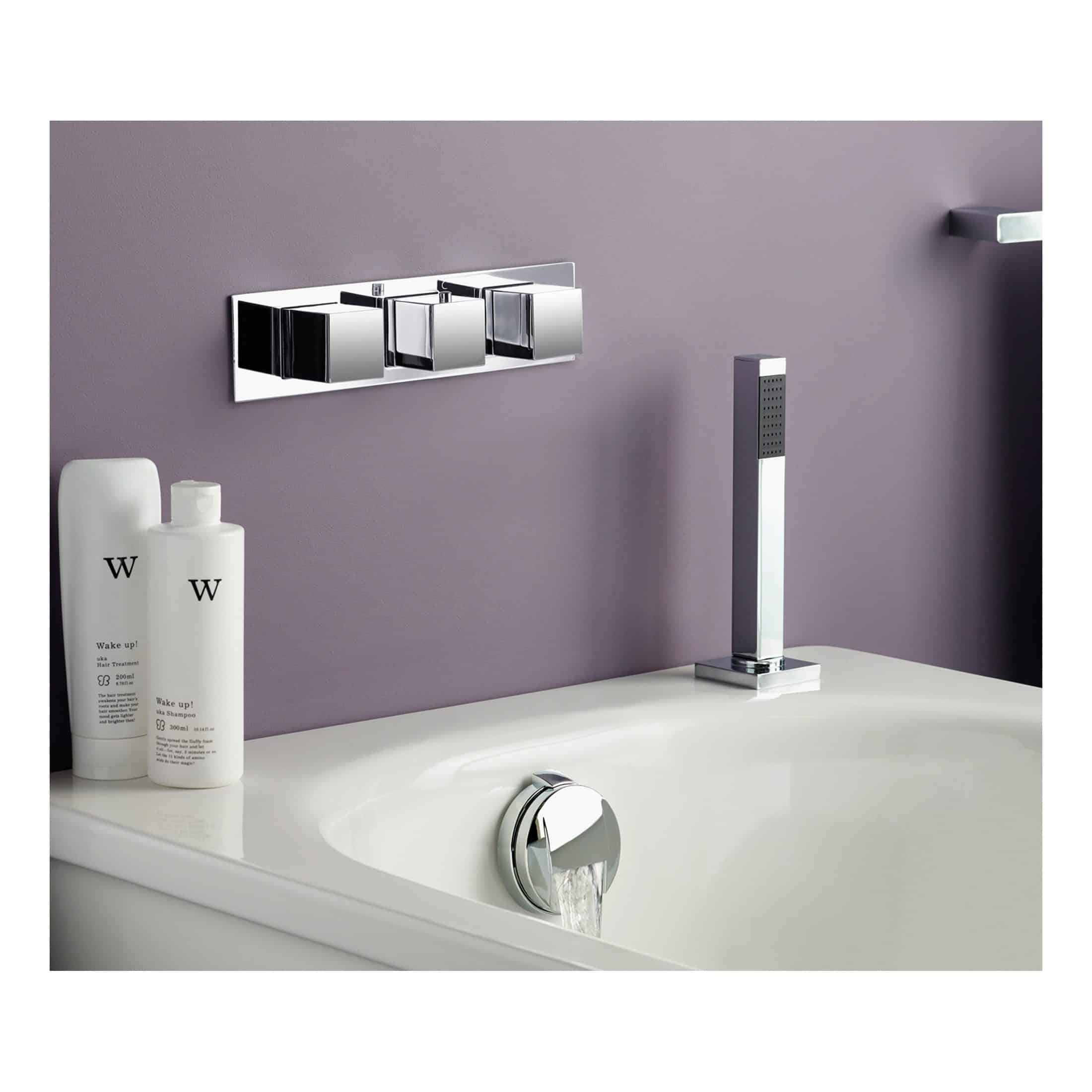 Sleek chrome bathroom tap and modern fixtures on a purple wall in a contemporary bathroom setting.