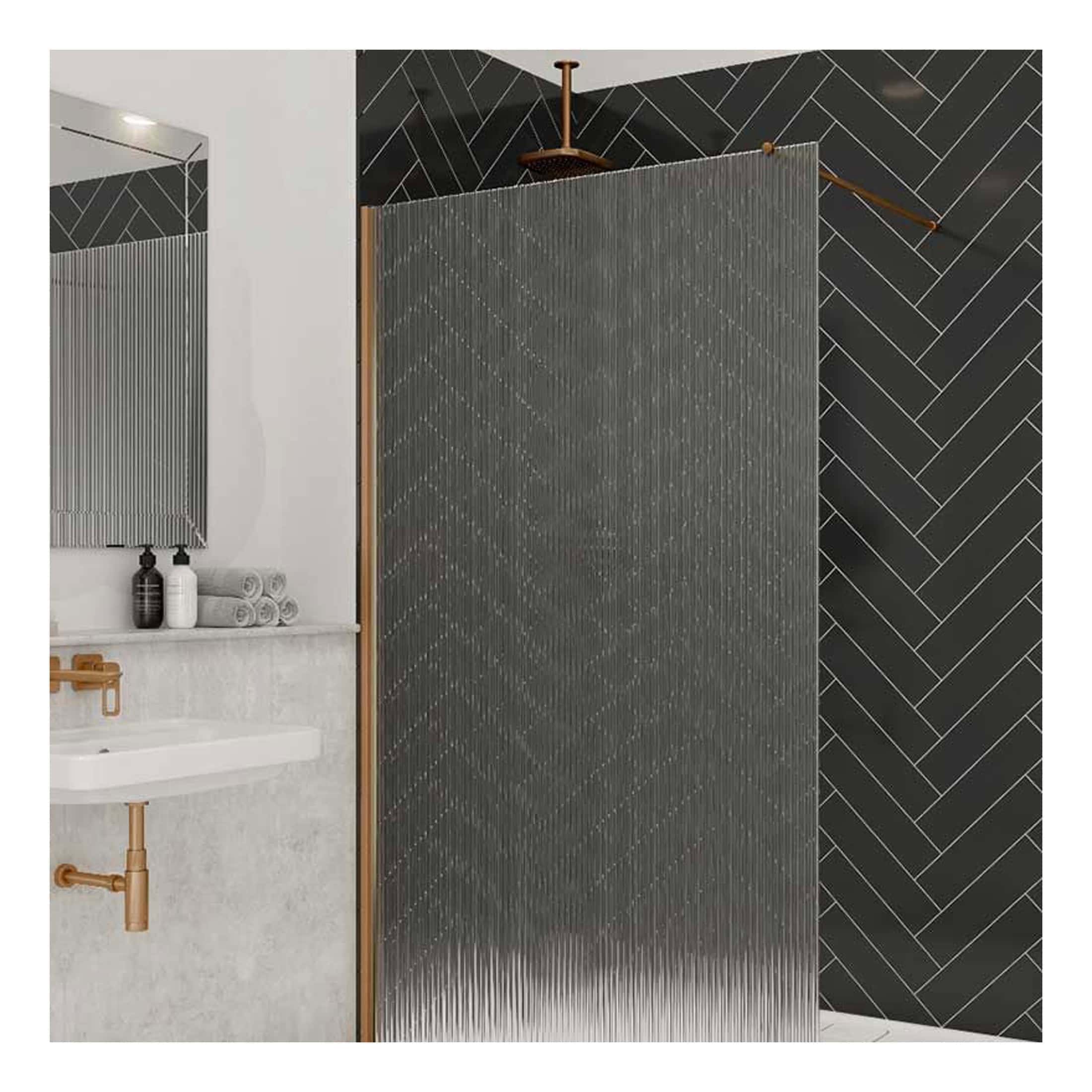 Sleek modern bathroom shower area with black herringbone tile wall, tempered glass partition, and minimalist white sink with copper fixtures, creating a contemporary bathroom design.