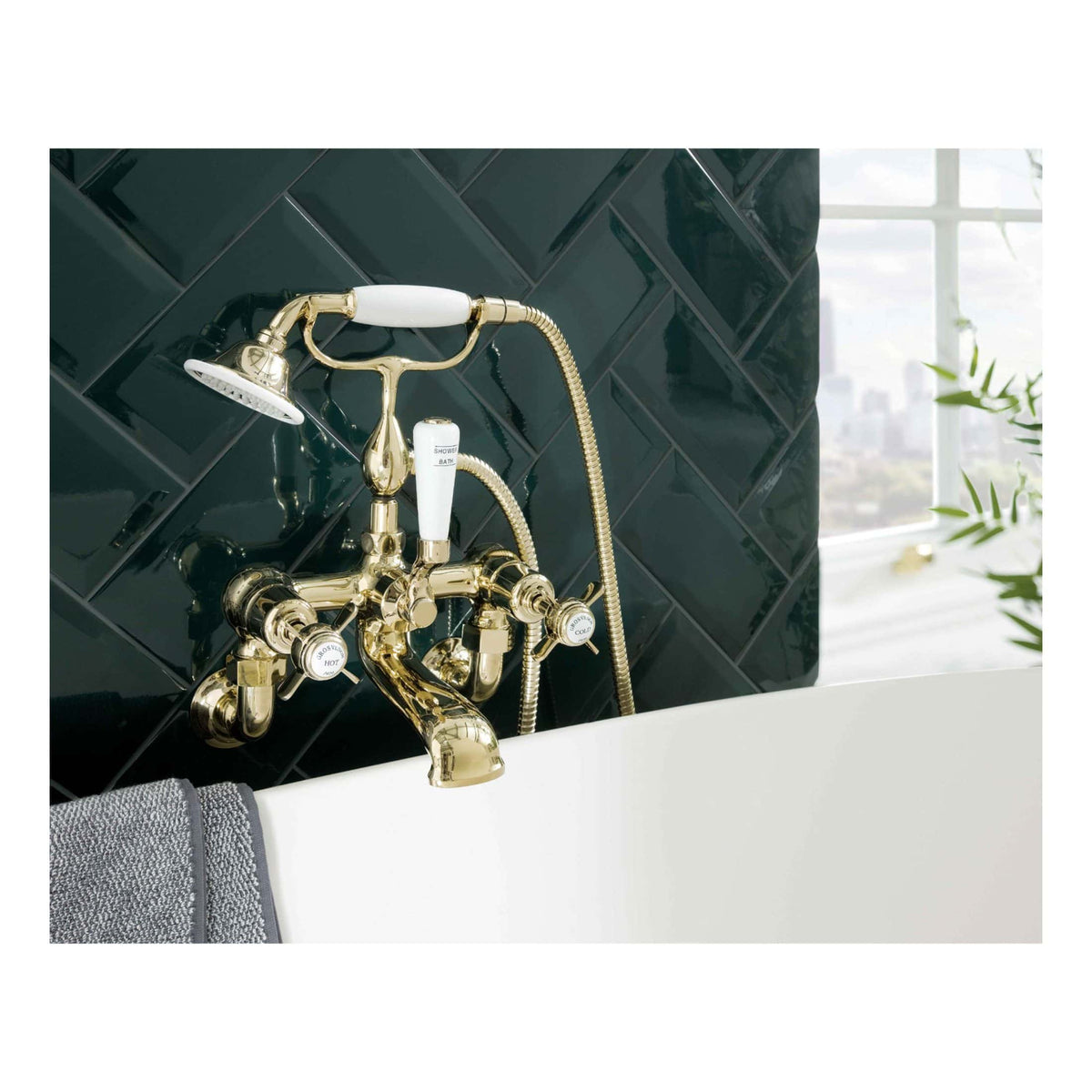 Brass vintage-style bathtub tap and showerhead with white ceramic handles, mounted above a modern white bath, against a sleek black tiled wall for luxury bathroom design.