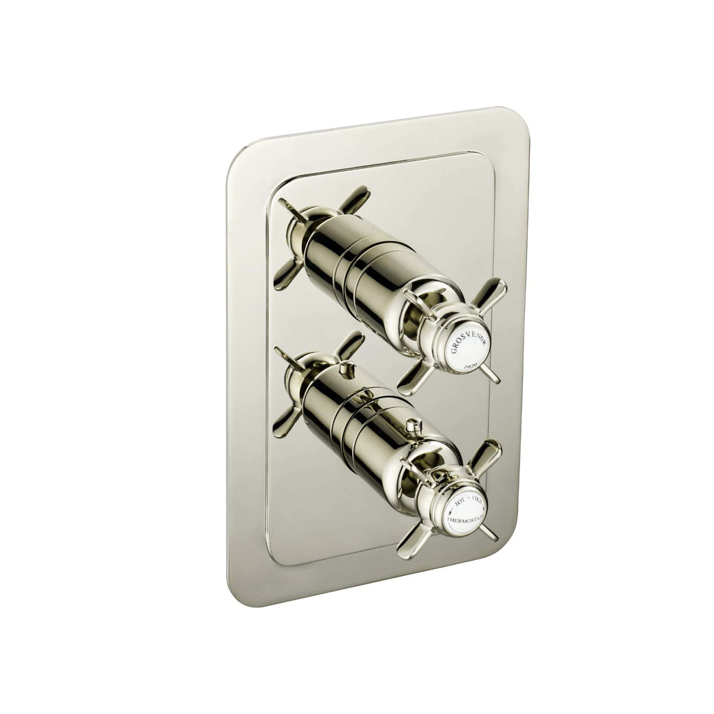 Shiny chrome bathroom mixer tap with dual handles mounted on a reflective metal plate for elegant bath or shower controls.