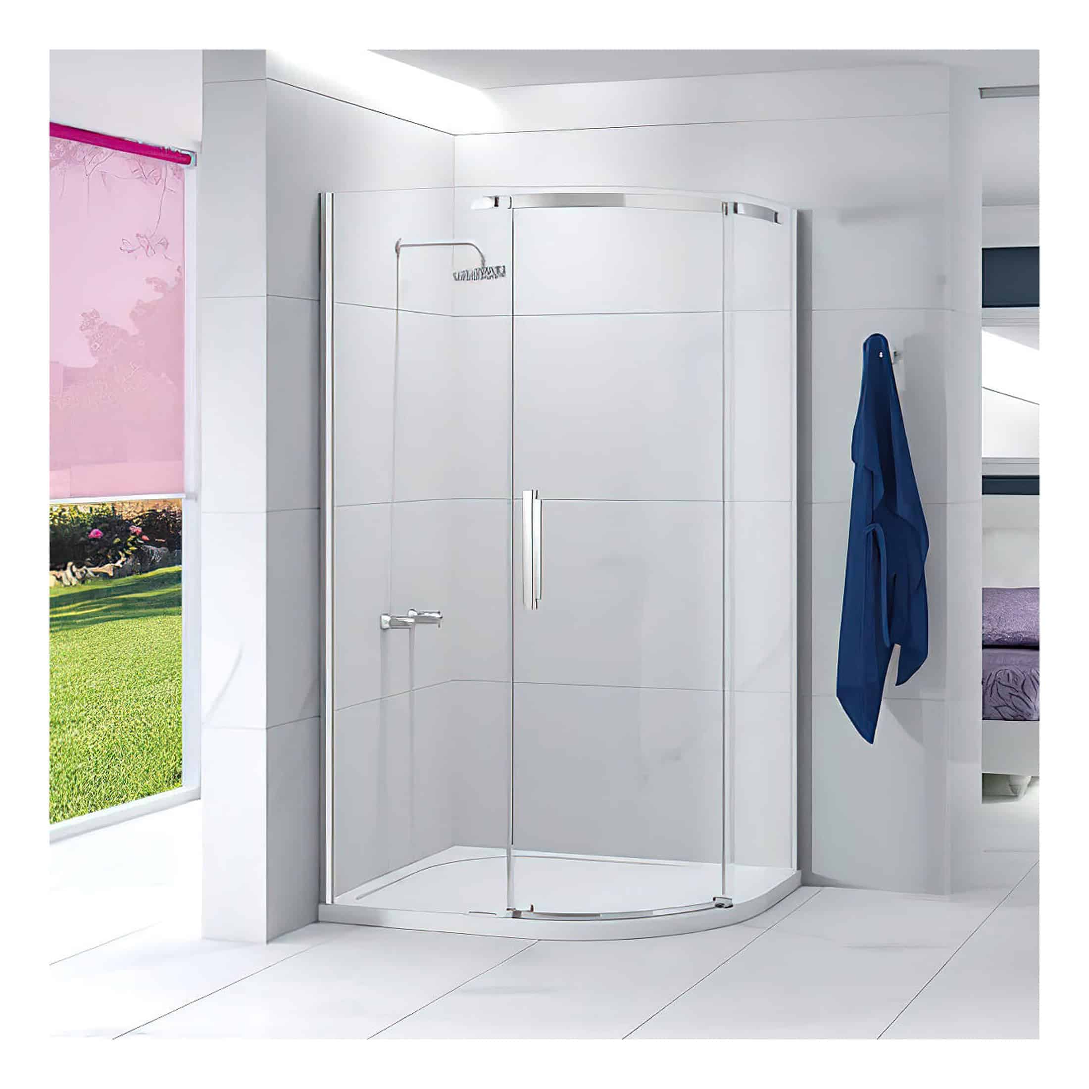 Shower enclosure with curved glass doors in a modern bathroom featuring white tiled walls and a blue towel hanging on a hook. Bright, clean design with natural light from a window showing a garden outside.