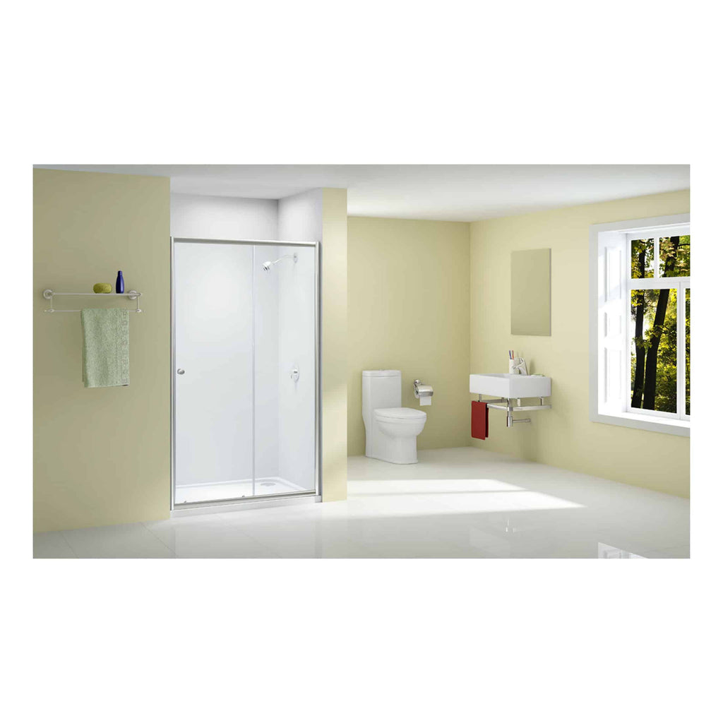 Shower enclosure with chrome frame, modern bathroom with toilet and sink, large window with greenery outside, light beige walls, minimalistic bathroom design.