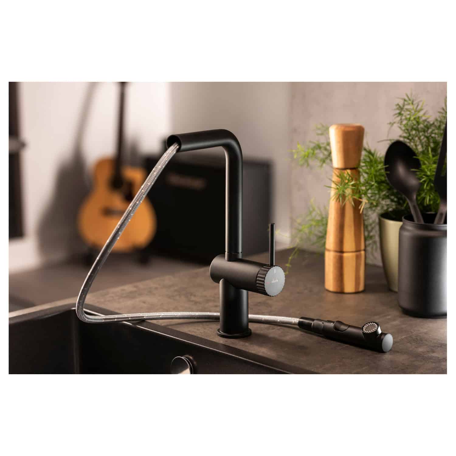 Sleek black kitchen faucet with pull-down spray head, modern design, and matte finish, installed on a dark countertop, surrounded by indoor plants, wooden pepper mill, and kitchen utensils, perfect for contemporary bathroom or kitchen upgrade.