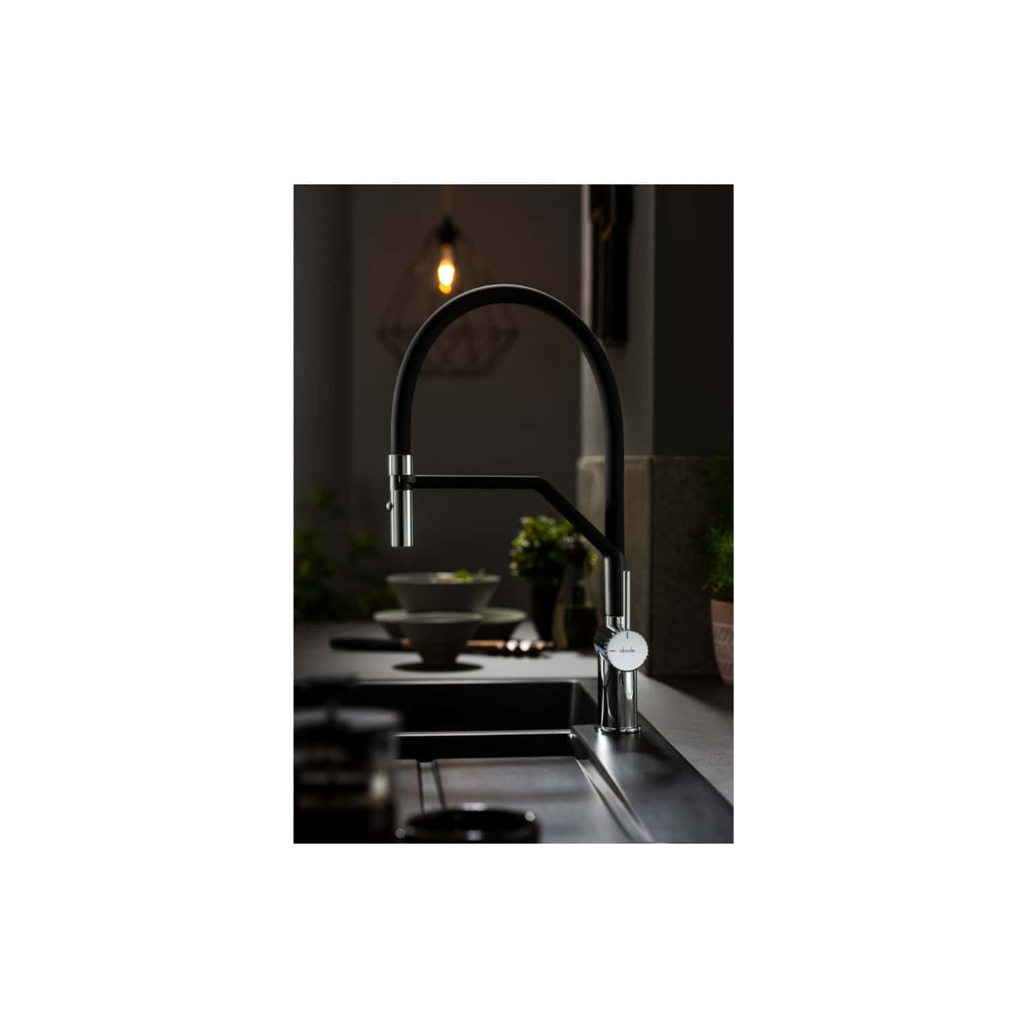 Sleek modern black kitchen tap with chrome accents, installed over a stainless steel sink, in a contemporary kitchen setting.
