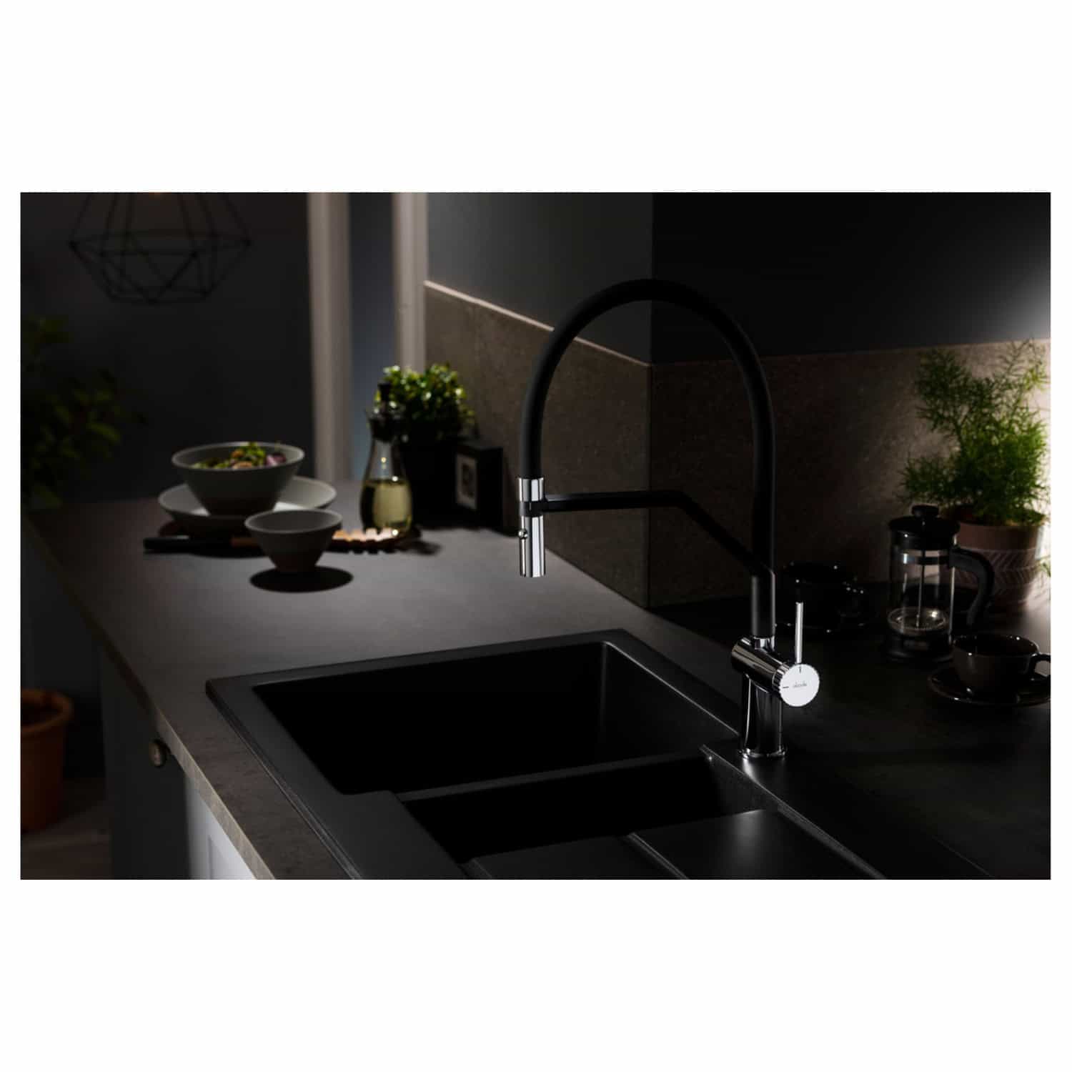 Sleek black kitchen sink with modern chrome faucet in a contemporary kitchen setting featuring dark tones, decorative plants, and elegant tableware. Perfect for stylish and functional kitchen updates.