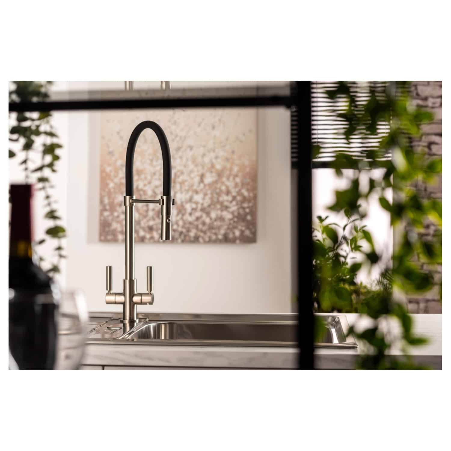 Sleek modern kitchen sink with a stylish black and stainless steel mixer tap, surrounded by lush green plants and contemporary decor. Perfect for a luxury bathroom or kitchen upgrade.