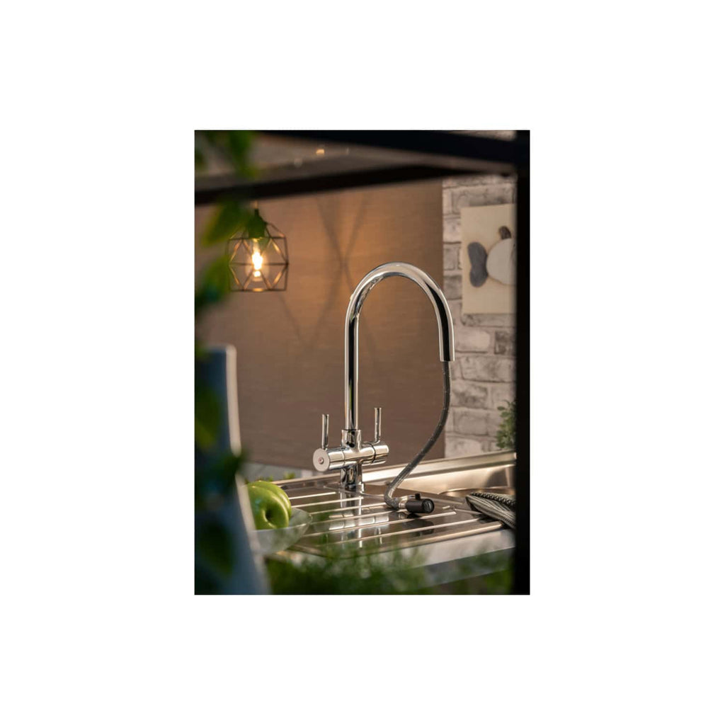 Shiny kitchen sink with modern chrome faucet and attached hose, set in a contemporary kitchen with warm lighting, potted plant, and decorative wall art, ideal for modern bathroom or kitchen renovation.