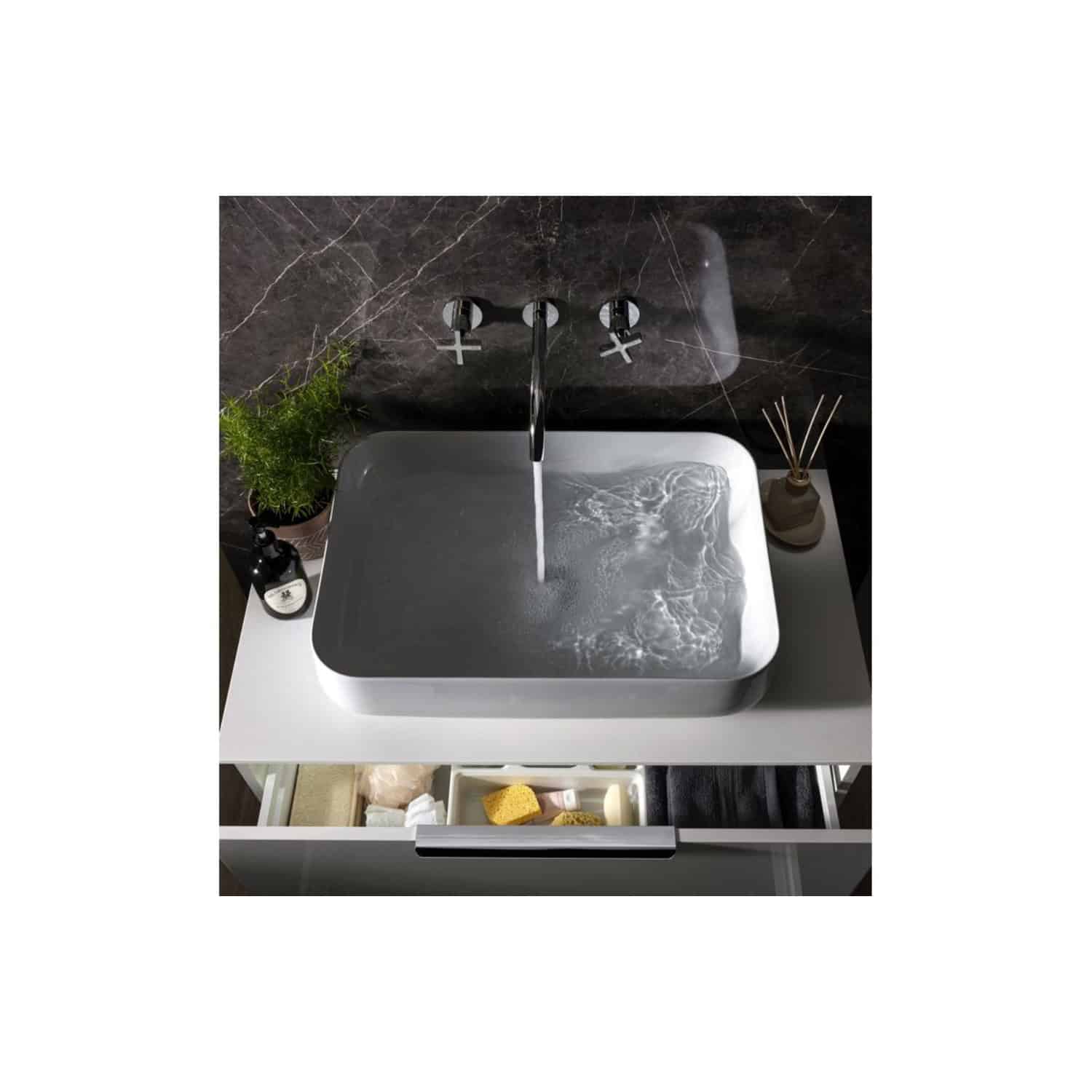 Elegant bathroom sink with a sleek black marble wall and modern chrome fixtures, complemented by stylish accessories and a functional storage drawer for toiletries.