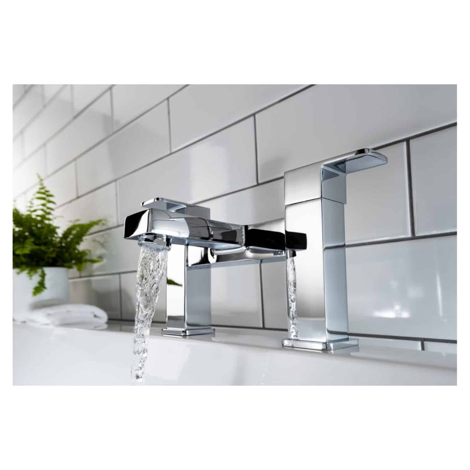 Shiny chrome bathroom tap with flowing water mounted on white tiled wall, modern bathroom accessories, elegant design for contemporary bathrooms.