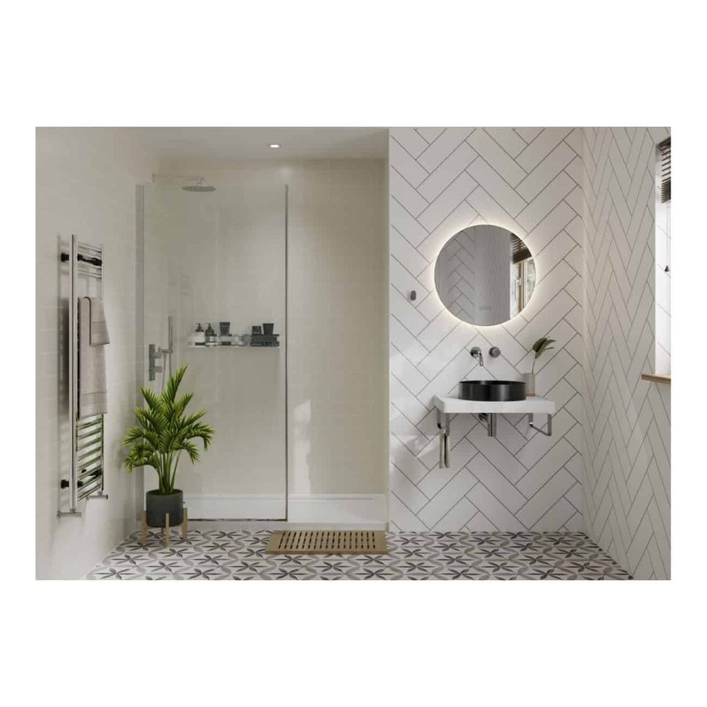 Contemporary bathroom with walk-in shower, circular mirror with backlighting, black basin sink, wall-mounted faucet, white geometric tile walls, patterned floor tiles, and modern decor including a plant and towel rail.