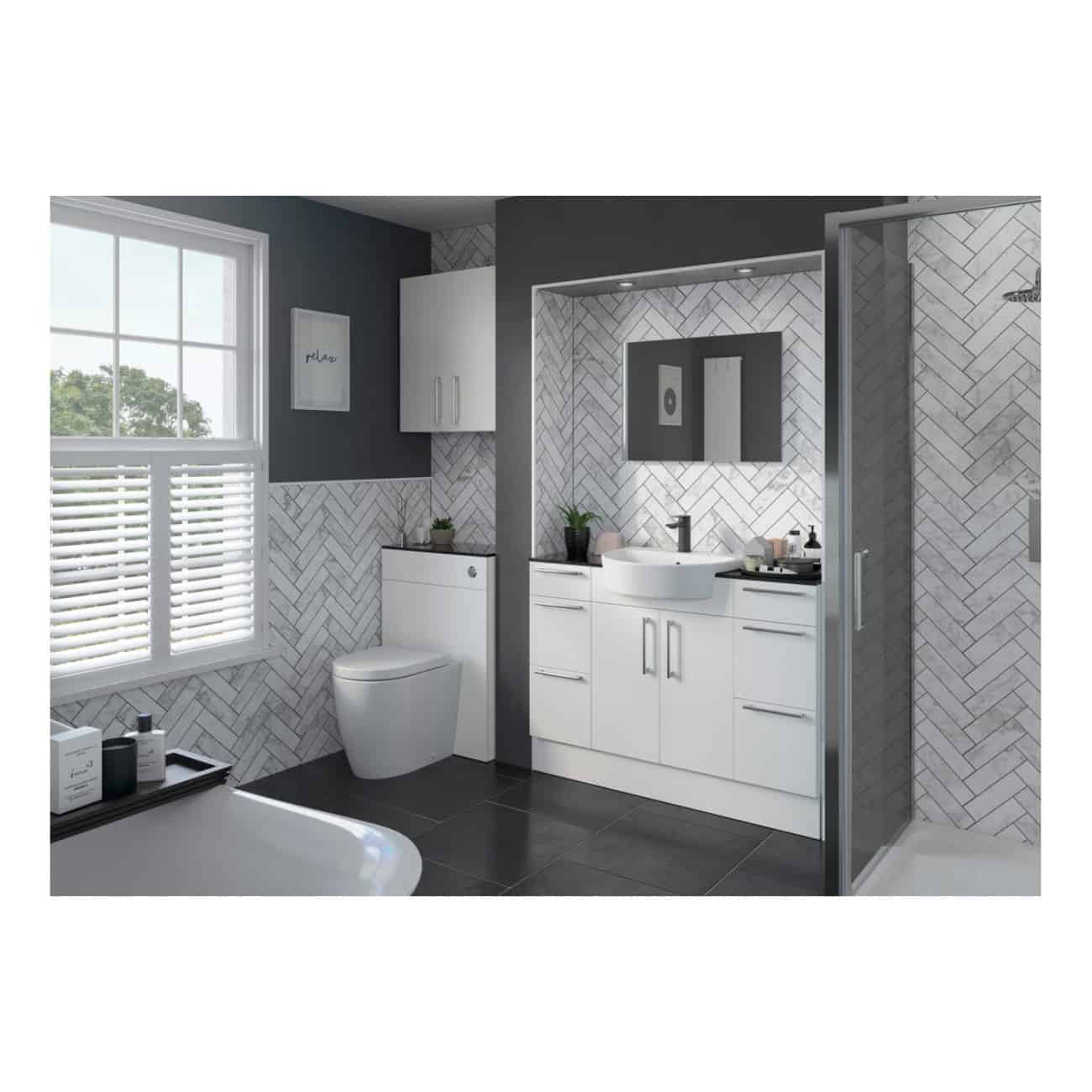 Modern bathroom with white vanity, grey tiled floor, rain shower enclosure, and grey and white herringbone wall tiles, creating a sleek, contemporary look. Natural light from the window brightens the space.