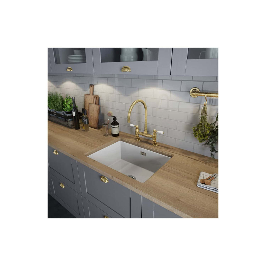 Sleek kitchen sink with brass fixtures, grey cabinetry, a wooden countertop, and modern lighting, perfect for contemporary bathroom or kitchen renovation projects.