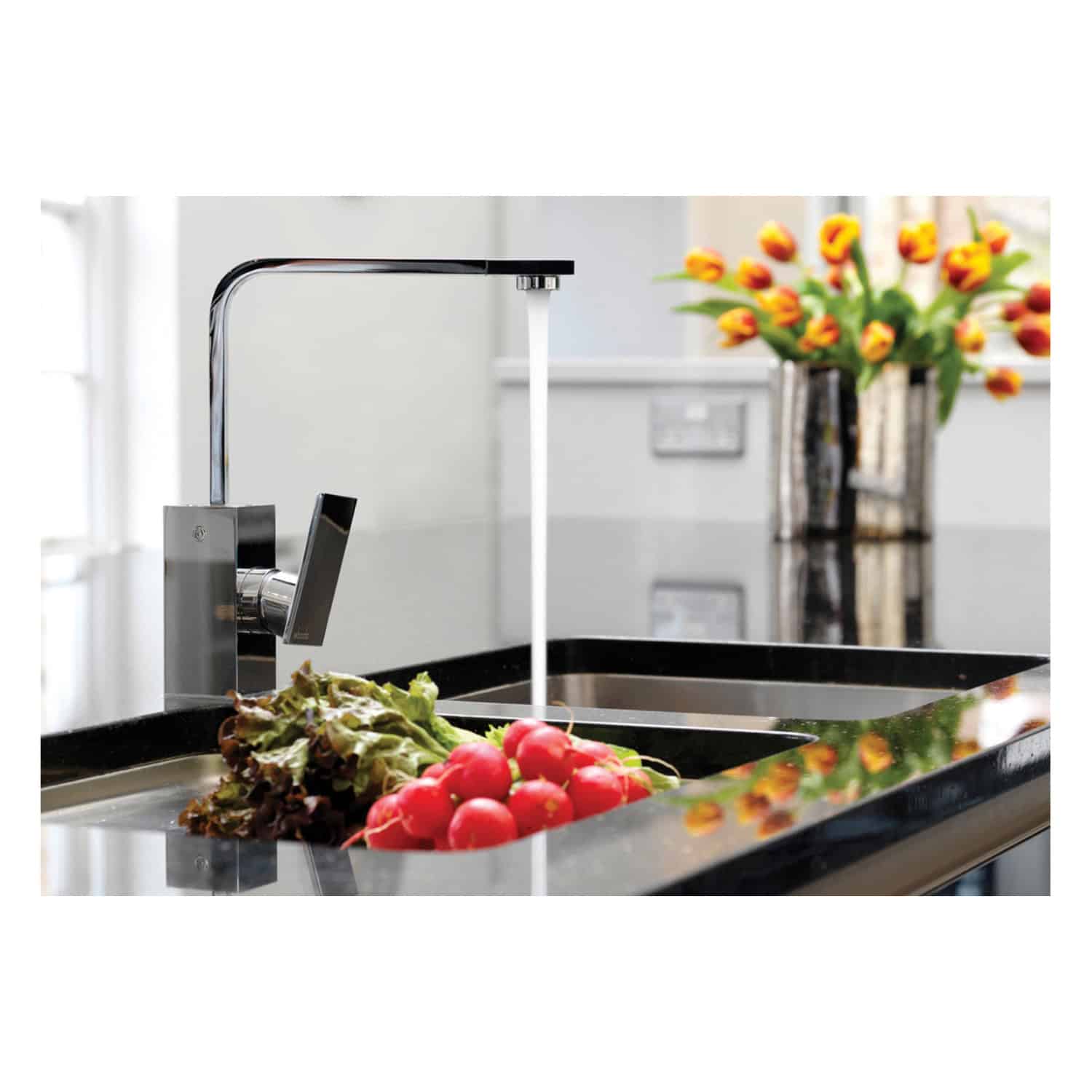 Fresh radishes and lettuce being washed at a modern kitchen sink with a sleek chrome tap, surrounded by a clean and bright environment with a vase of colourful tulips in the background.