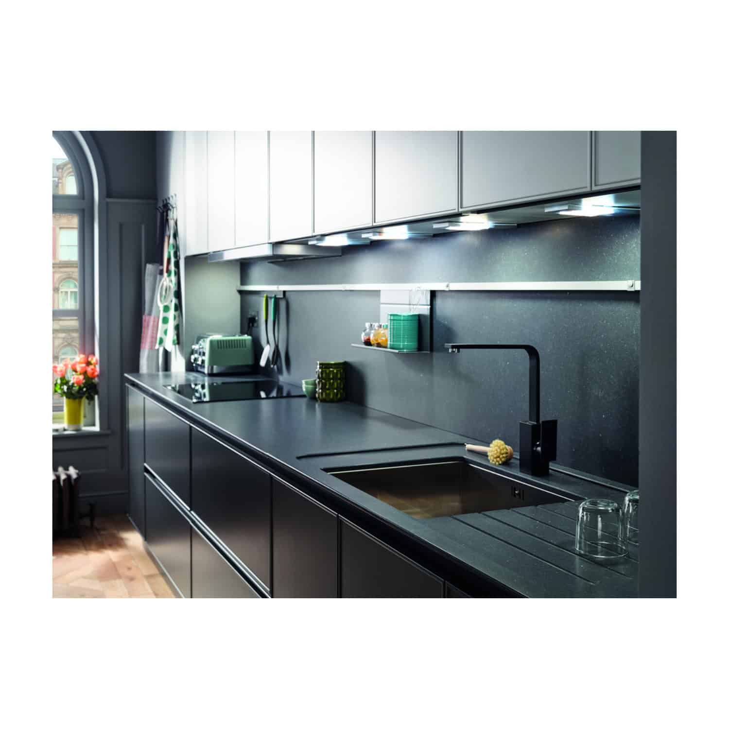 Sleek black kitchen countertop with modern minimalist design, under-cabinet lighting, and built-in sink, featuring kitchen essentials and a contemporary aesthetic.