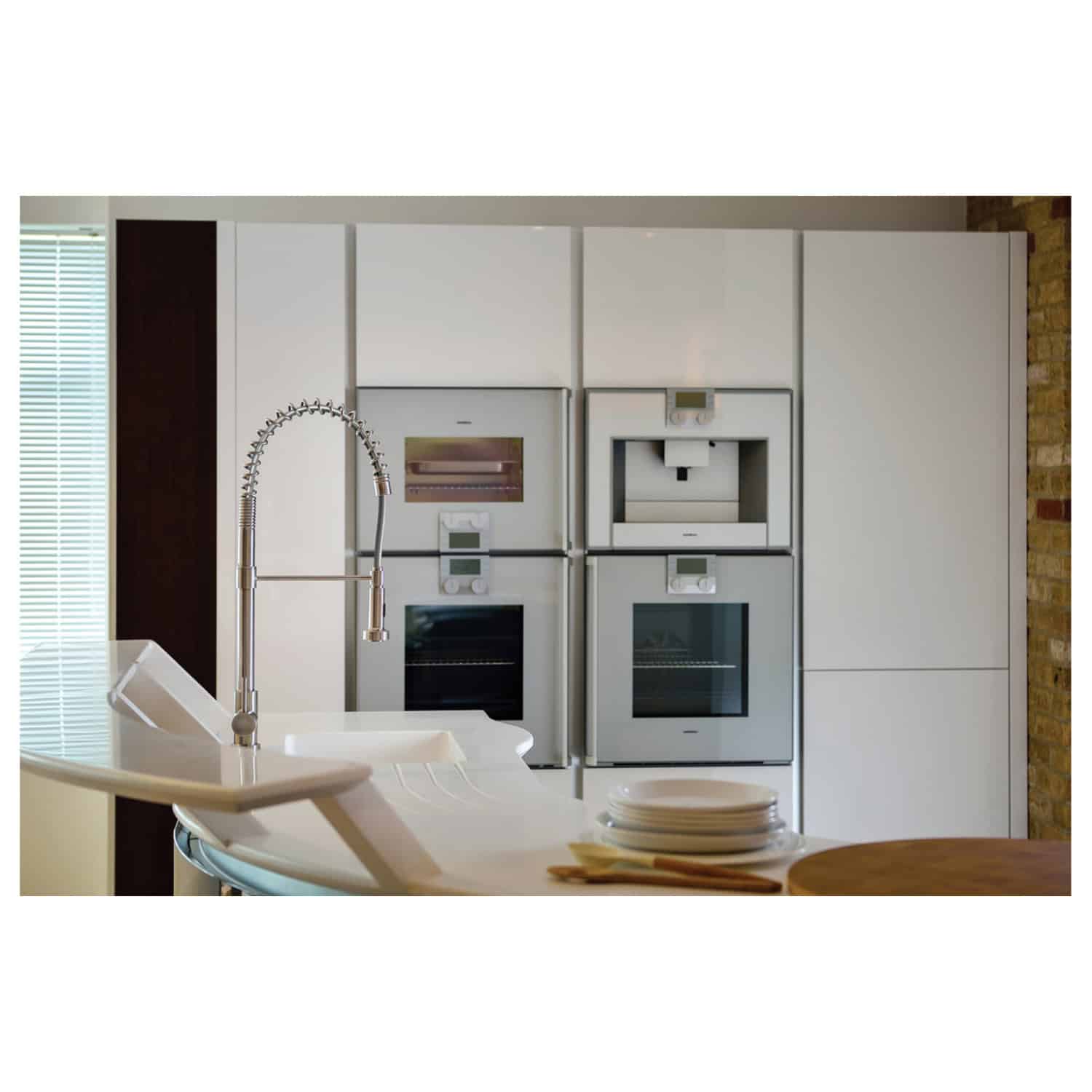 Modern sleek kitchen with integrated appliances and a contemporary white countertop with a built-in stainless steel faucet. Perfect for stylish, functional cooking and entertaining spaces.