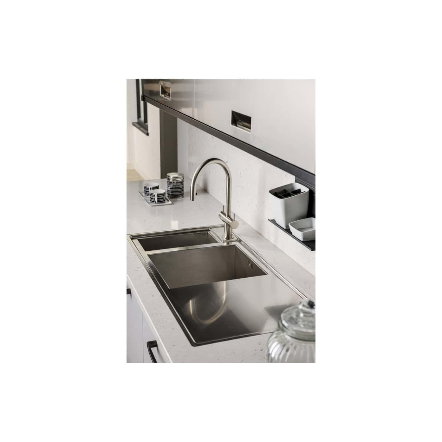 Stainless steel kitchen sink with modern faucet in a contemporary bathroom setting. Features clean design, white countertop, and organised accessories for optimal bathroom functionality.