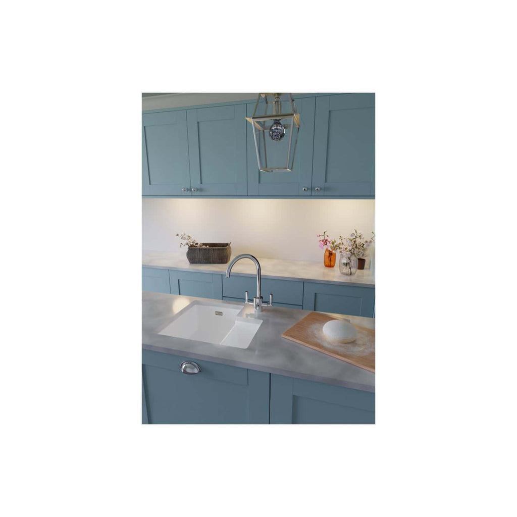 Elegant blue kitchen with marble countertops, modern sink, and decorative vases featuring flowers, perfect for contemporary bathroom or kitchen design.