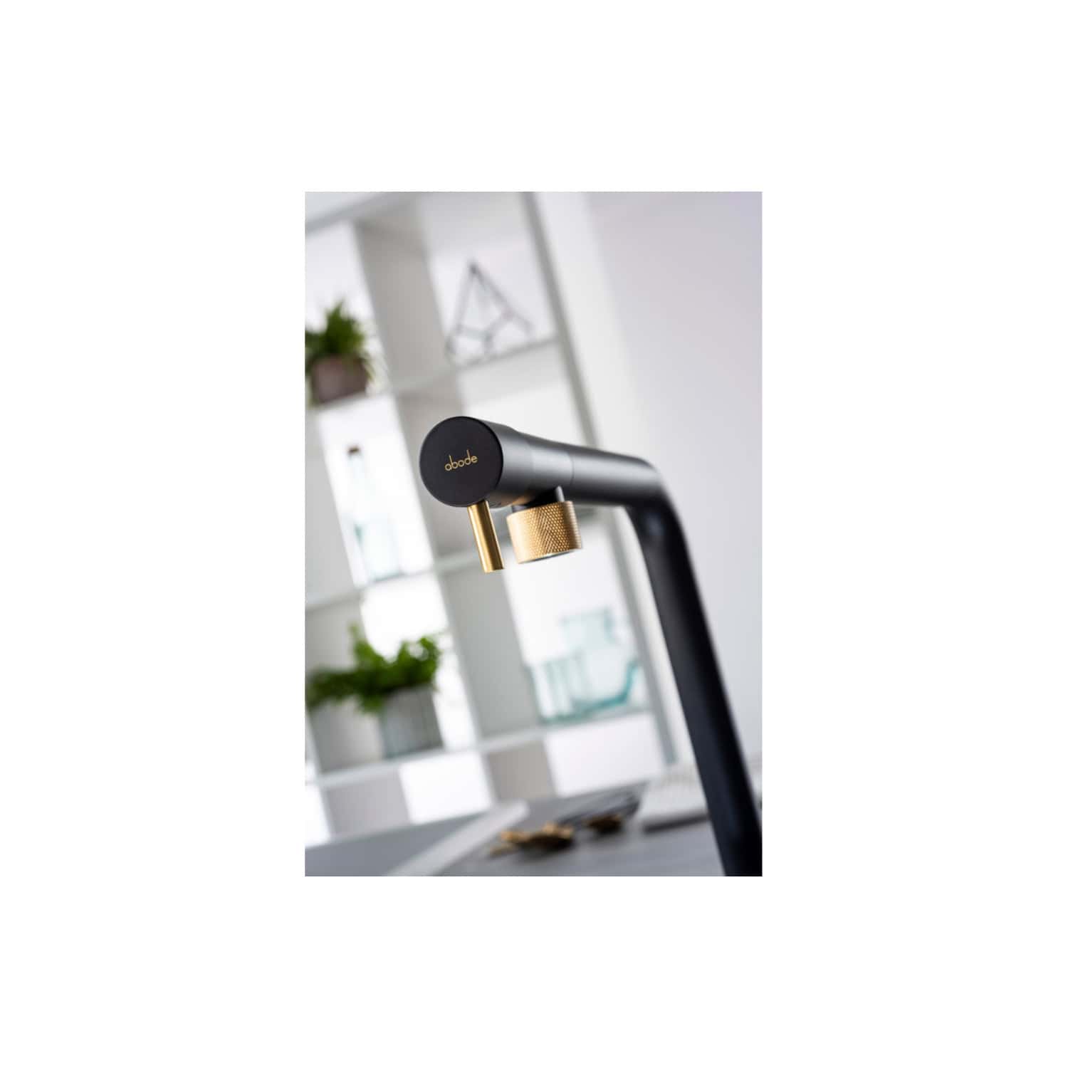 Sleek modern black and gold bathroom tap with "abode" branding, stylish kitchen or bathroom fixture designed for contemporary homes, featuring minimalist design and premium metallic accents.