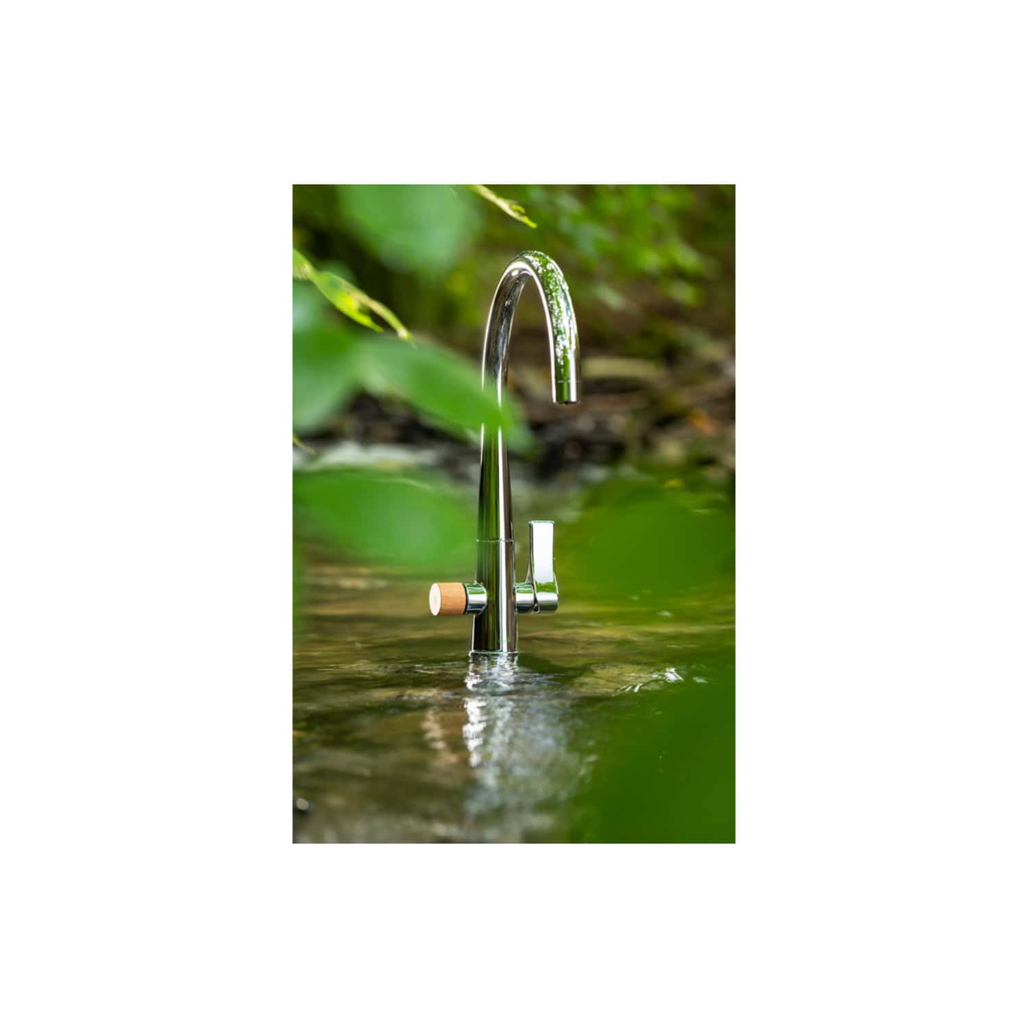 Shiny modern koi fish kitchen tap installed outdoors amongst greenery, near water, highlighting eco-friendly and stylish bathroom and kitchen fixtures. Perfect for stylish, eco-conscious home design.