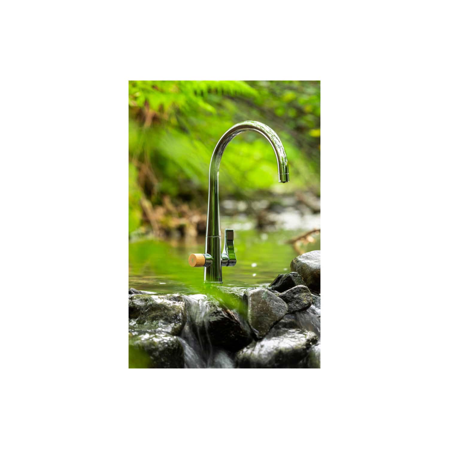 Futuristic outdoor brass bathroom faucet mounted on rocks near a flowing stream with lush green foliage in the background, showcasing eco-friendly outdoor plumbing solutions.