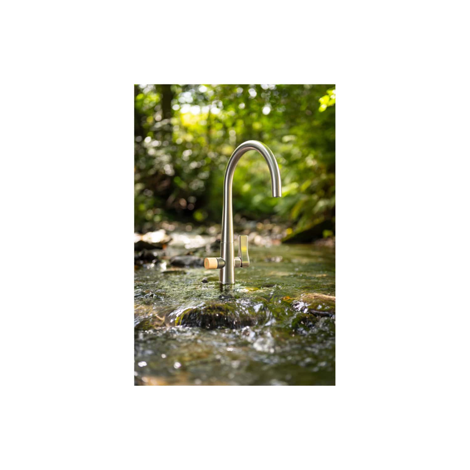 Stainless steel outdoor kitchen faucet in stream of flowing water surrounded by lush greenery, eco-friendly garden water feature, outdoor plumbing fixture, modern garden design, durable water tap, Bubly Bathrooms.