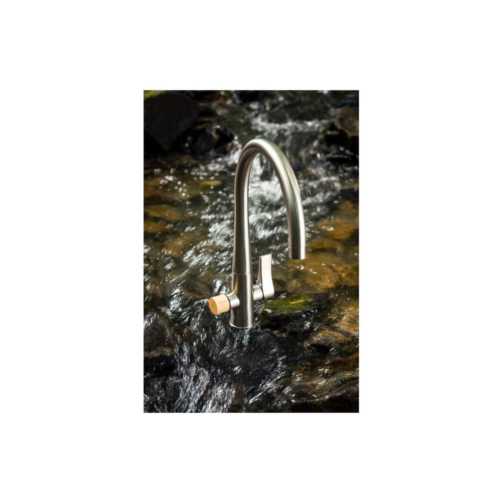 Sleek stainless steel kitchen and bathroom tap installed in a natural outdoor setting with flowing water. Perfect for outdoor kitchens or eco-friendly bathrooms.