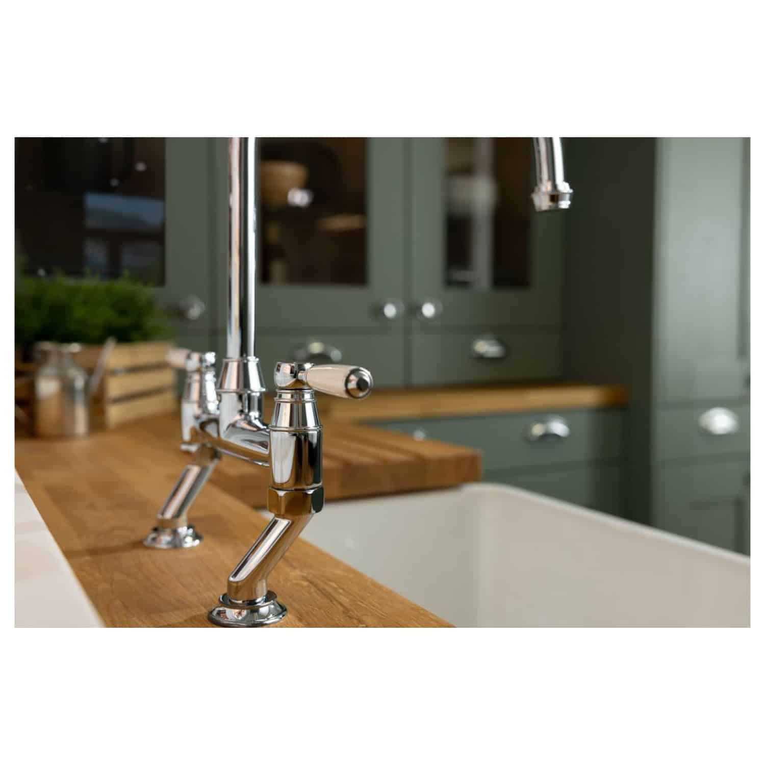 Sleek chrome kitchen sink tap with modern design, fitted on a wooden countertop in a contemporary kitchen with green cabinetry, ideal for stylish bathroom renovations or kitchen upgrades.