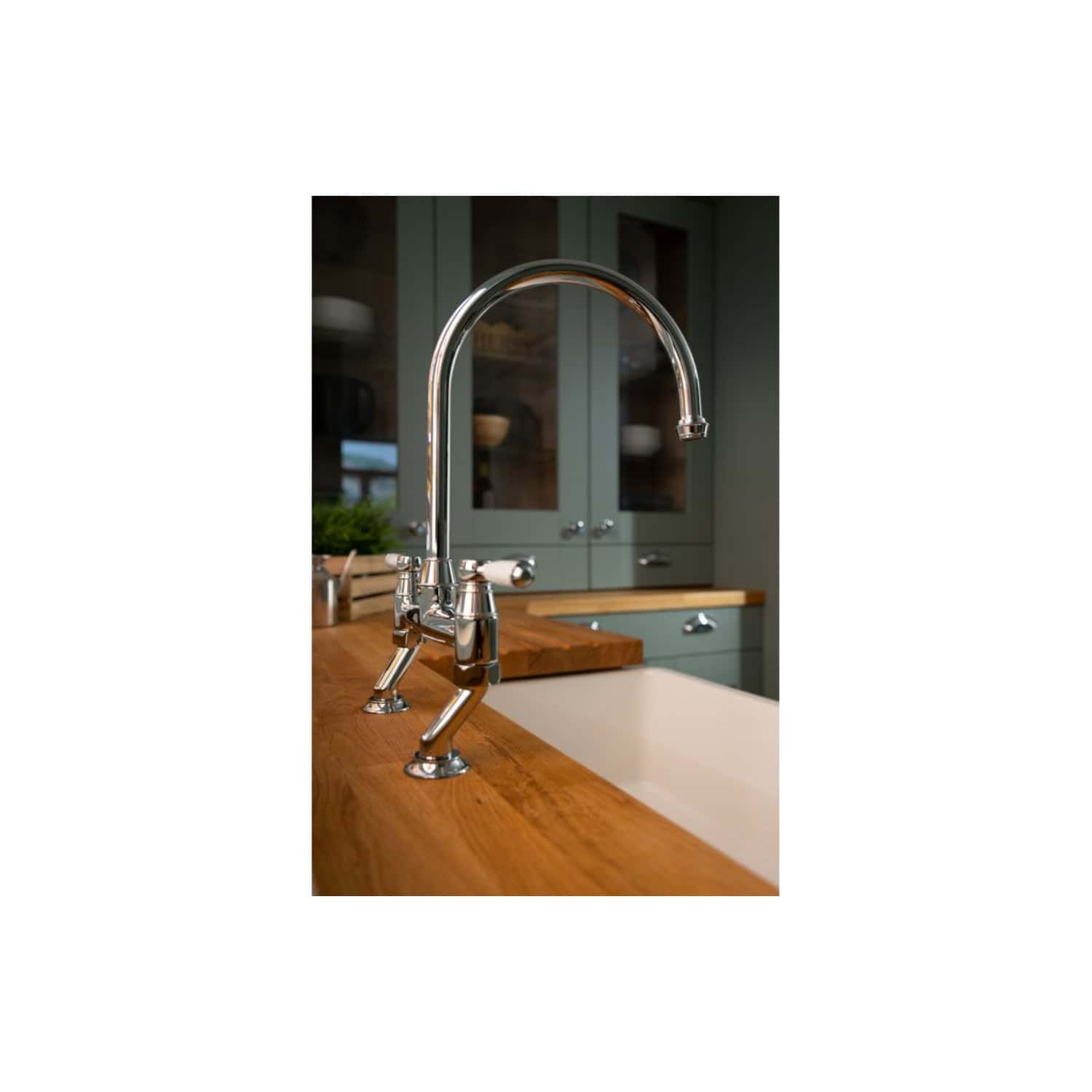 Sleek chrome kitchen sink tap with high arc design, installed on a wooden countertop in a modern kitchen with green cabinetry, combining style and functionality for contemporary kitchen spaces.
