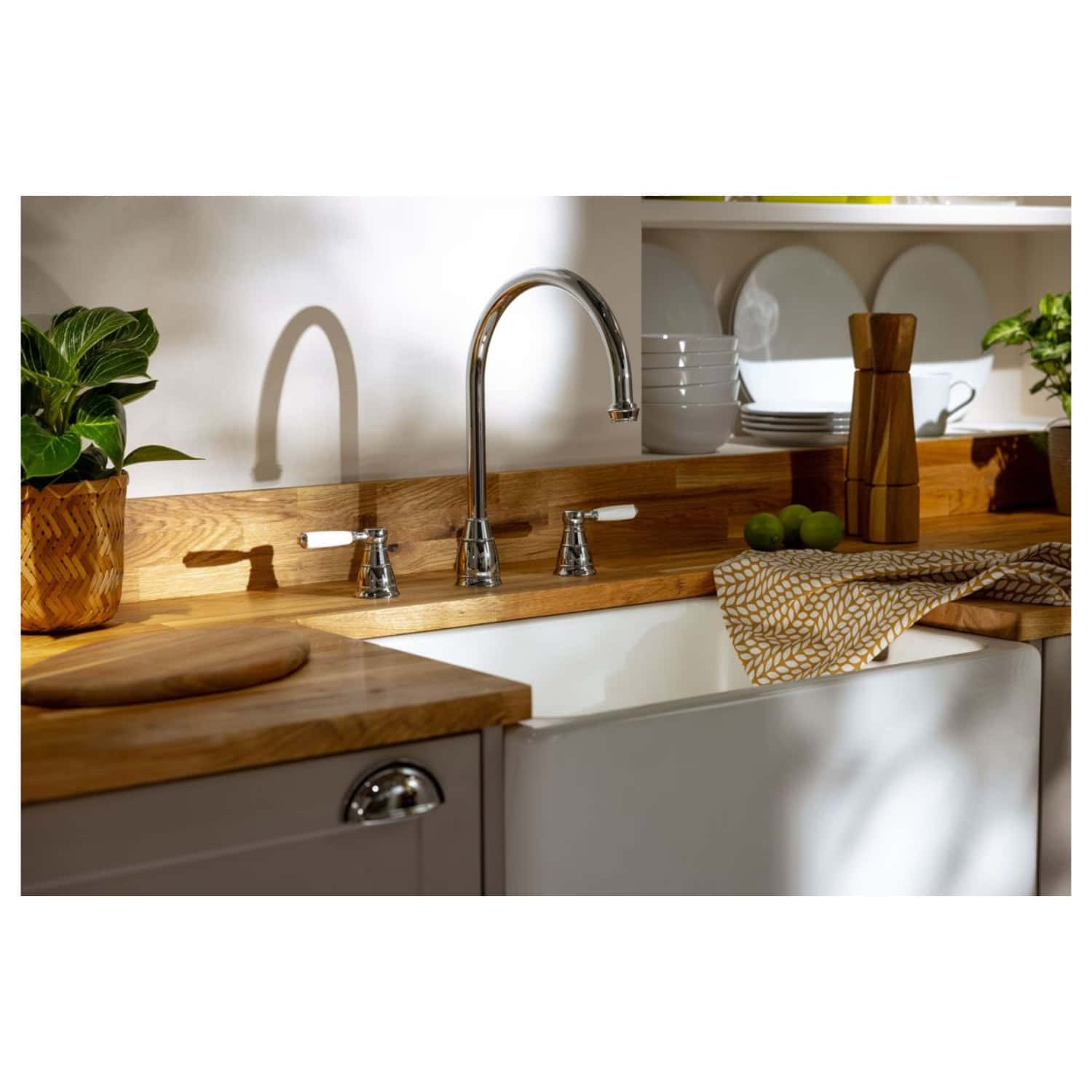 Polished chrome kitchen tap with hot and cold handles in a rustic farmhouse kitchen setting.