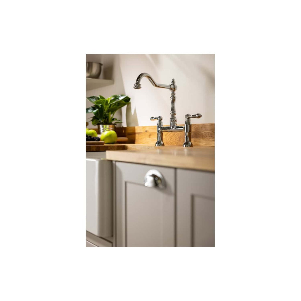 Shiny chrome kitchen sink faucet in a modern kitchen with beige cabinetry, wooden countertop, and fresh green apples and houseplants for a stylish, functional space.