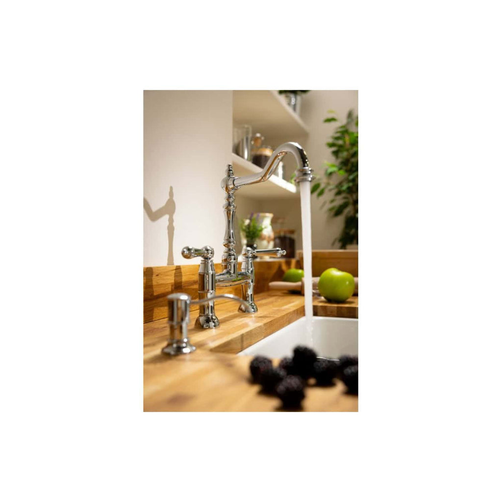Brushed nickel kitchen tap with flowing water, set on a wooden countertop with green apples and berries, featuring a modern bathroom or kitchen design with lush greenery in the background.
