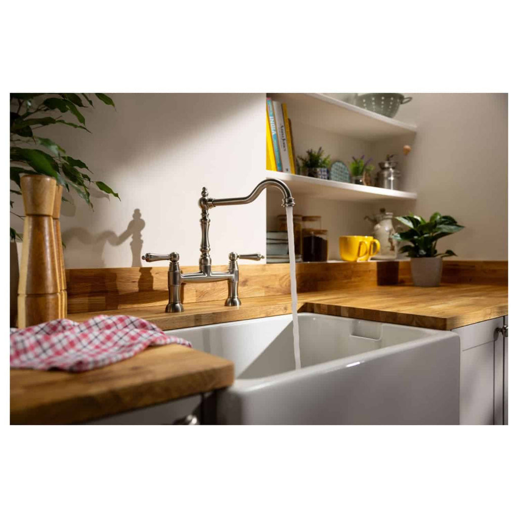 Bright kitchen with farmhouse sink and vintage-style chrome faucet, wooden countertops, open shelving with plants, books, and colourful mugs, showcasing stylish and functional bathroom design ideas by Bubly Bathrooms.