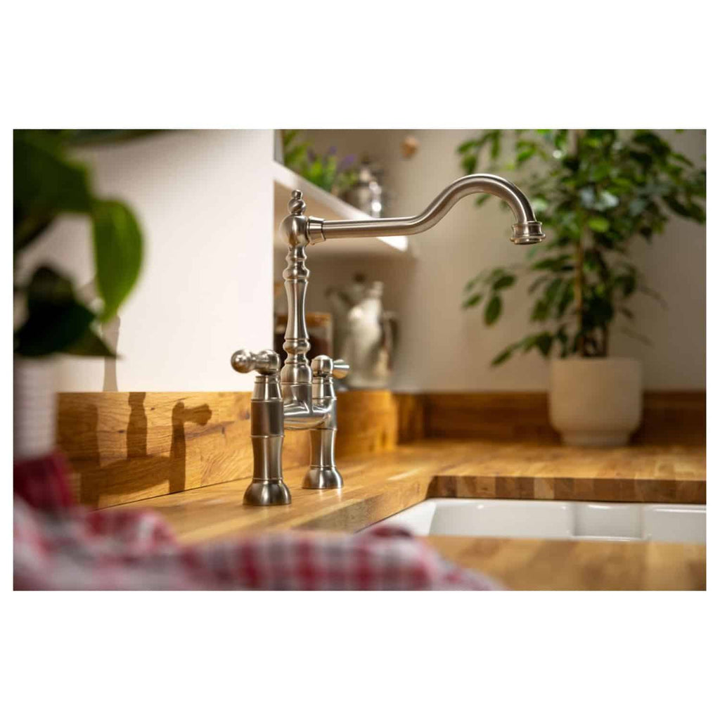 Sleek stainless steel kitchen tap on a wooden countertop with a white sink, surrounded by potted plants, showcasing modern bathroom and kitchen fixtures. Perfect for stylish kitchen or bathroom renovations.