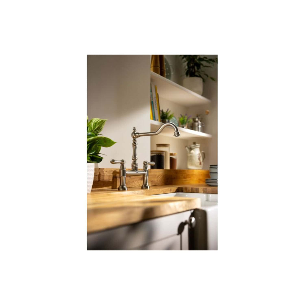 Polished vintage-style kitchen sink tap with a wooden countertop and open shelves with kitchenware, plants, and decorative items, creating a modern yet classic kitchen aesthetic.