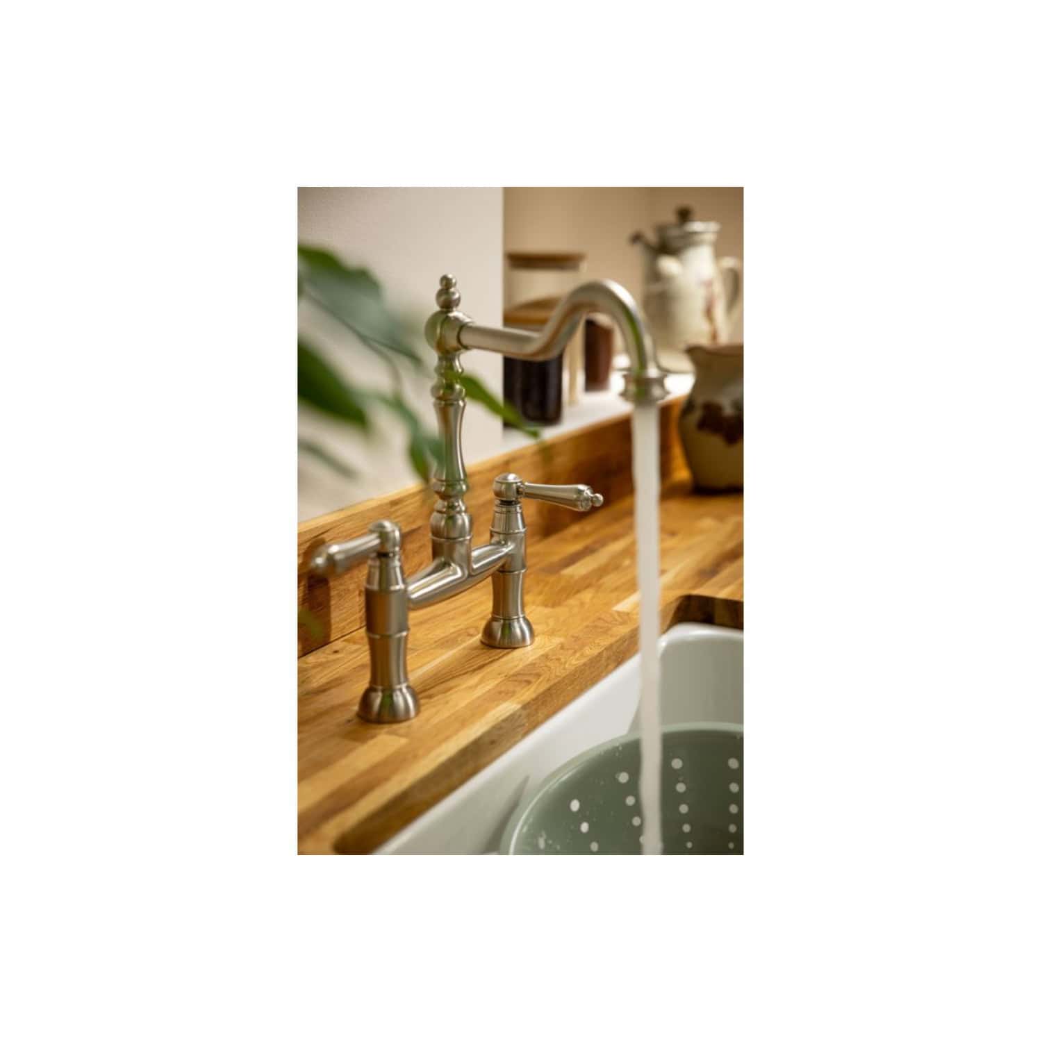 Brushed nickel kitchen tap with hot and cold handles, installed over a wooden countertop with a white ceramic sink for a stylish bathroom or kitchen renovation.