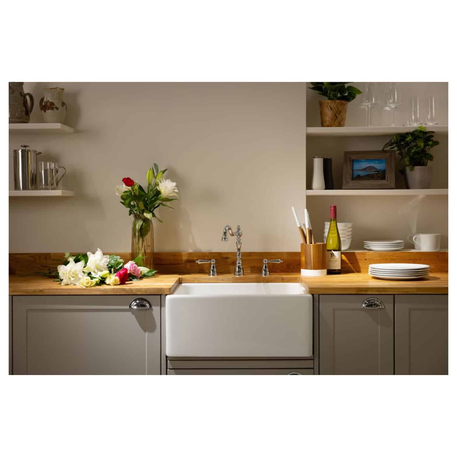 Vintage farmhouse kitchen with farmhouse sink and open shelving; warm wood countertops, fresh flowers, and decorative tableware create a cozy, inviting atmosphere. Perfect for rustic or country-style kitchens.