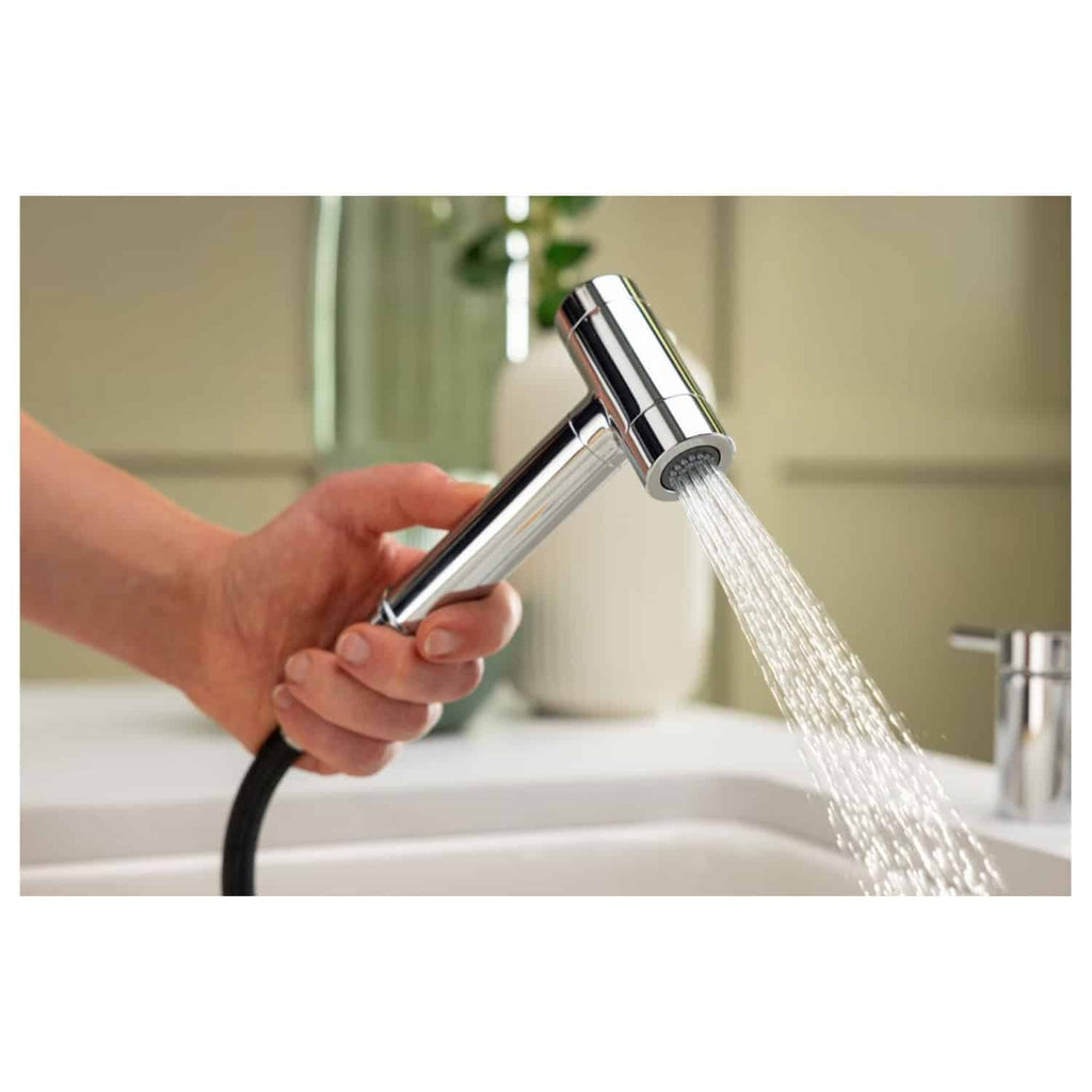 Shiny chrome handheld bathroom faucet with a connected flexible black hose, water flowing for washing. Modern, sleek bathroom fixtures for style and functionality.