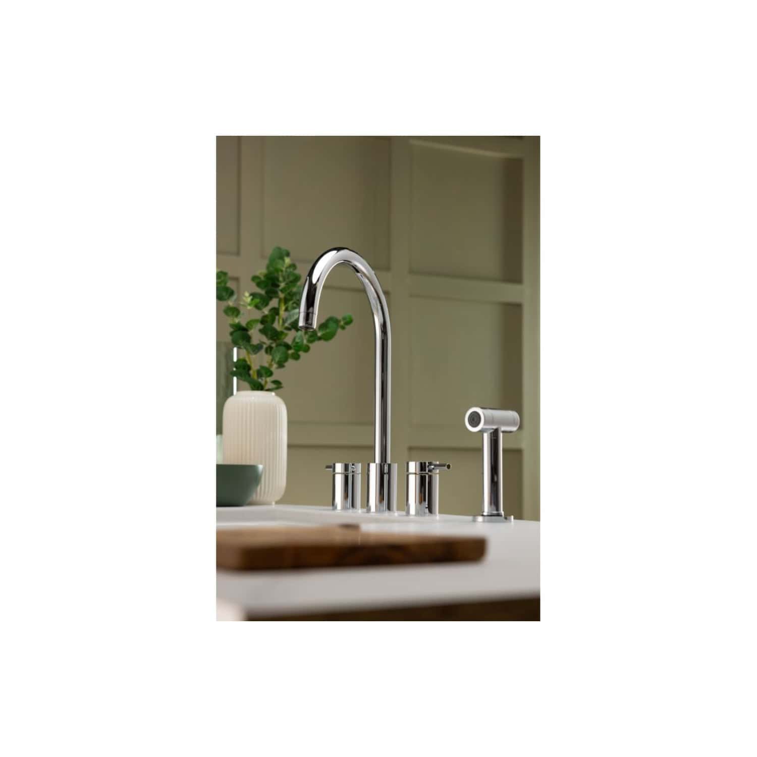 Shiny modern chrome kitchen sink faucet with pull-out spray, elegant design, and surrounding accessories in a contemporary kitchen setting.