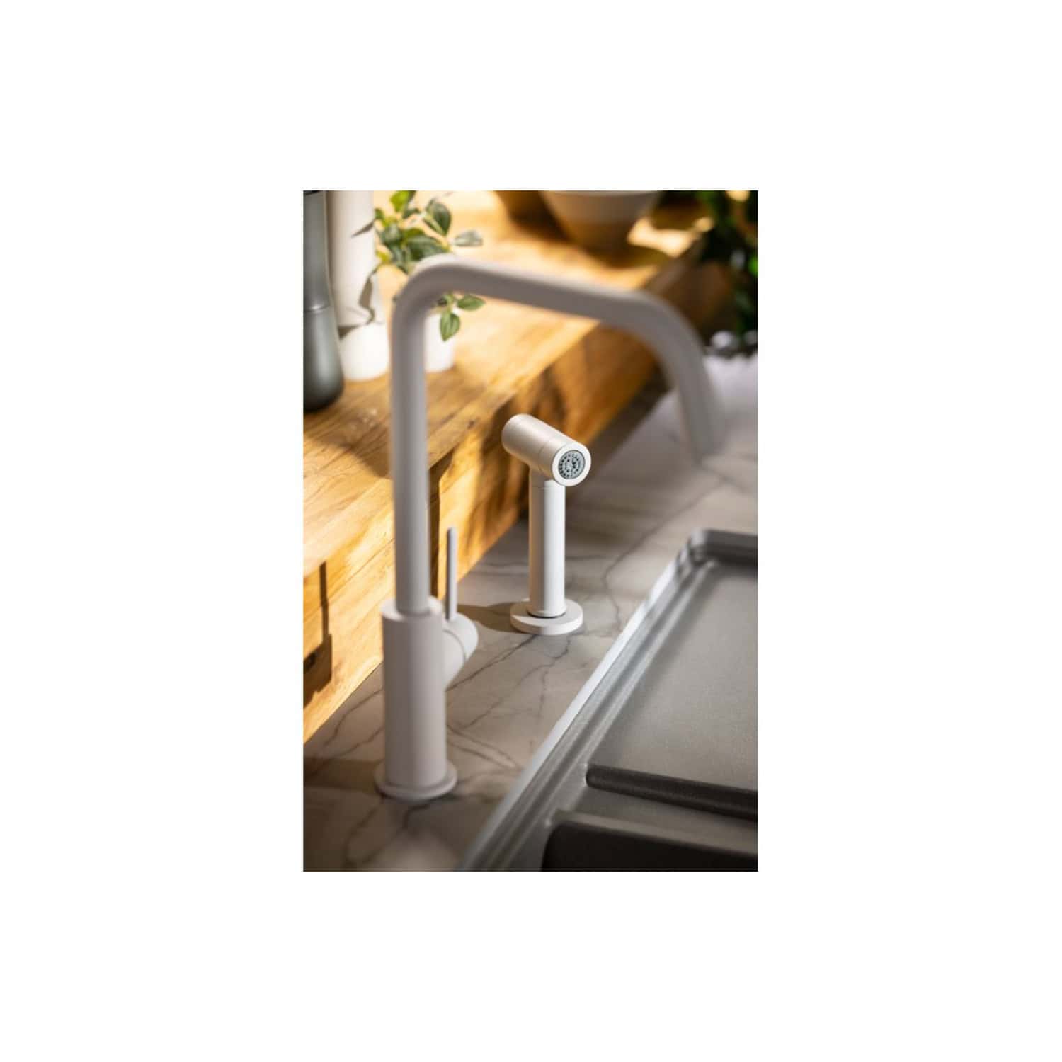 Sleek white kitchen tap with modern design and pull-down spray head, installed on a marble countertop in a contemporary kitchen setting.