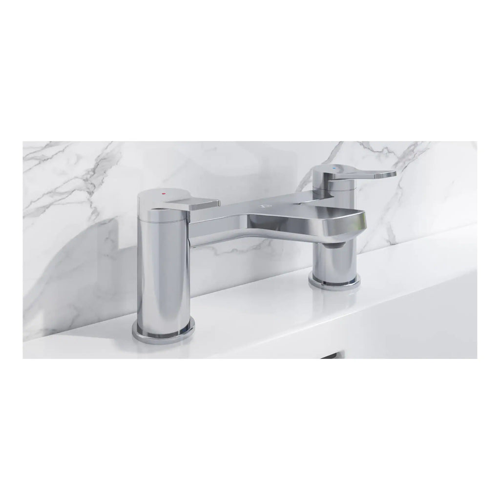 Sleek modern chrome bathroom tap with dual handles installed on a white basin against a marble wall.