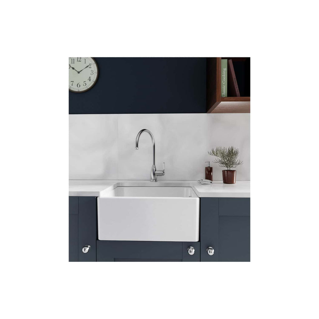 A modern kitchen sink with a sleek chrome faucet set against a navy blue and white colour scheme, featuring minimalist cabinetry, a wall clock, and decorative potted plants for contemporary ambiance.