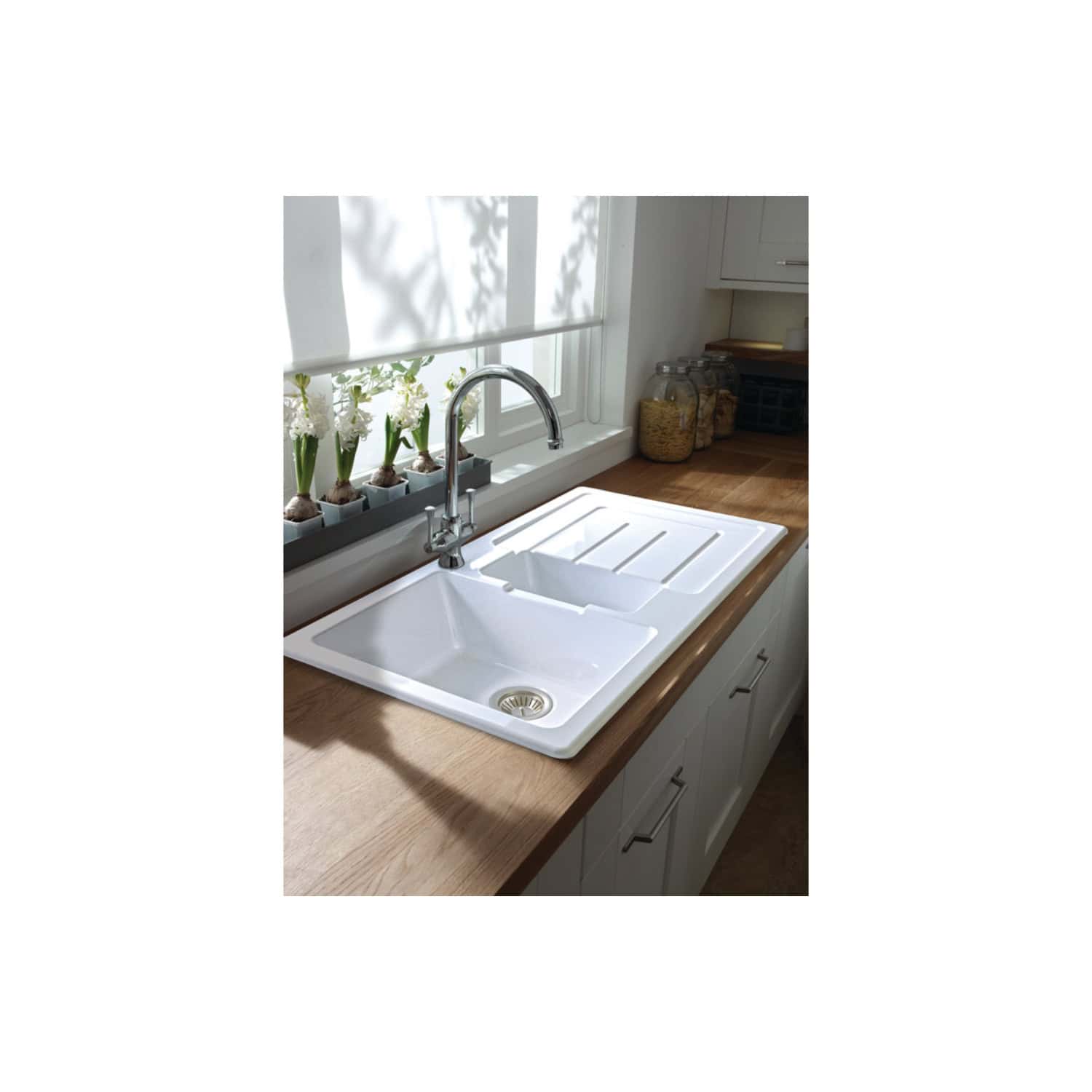 Sleek white ceramic kitchen sink with drainer and chrome tap in a bright, modern kitchen setting. Perfect for stylish and functional kitchen design in UK homes.
