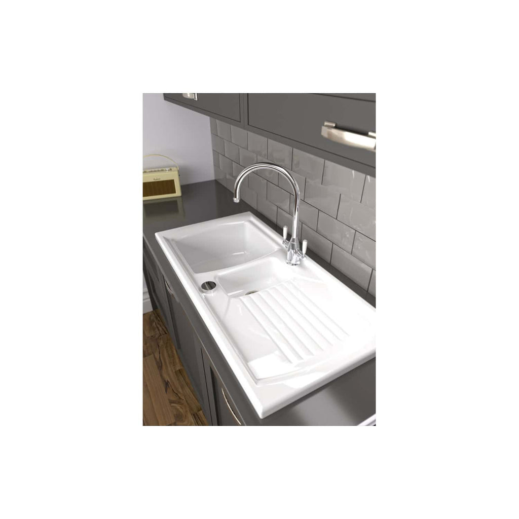 Stainless steel kitchen sink with draining board, chrome mixer tap, grey cabinetry, tiled backsplash, and wooden flooring, ideal for modern bathrooms and kitchens.