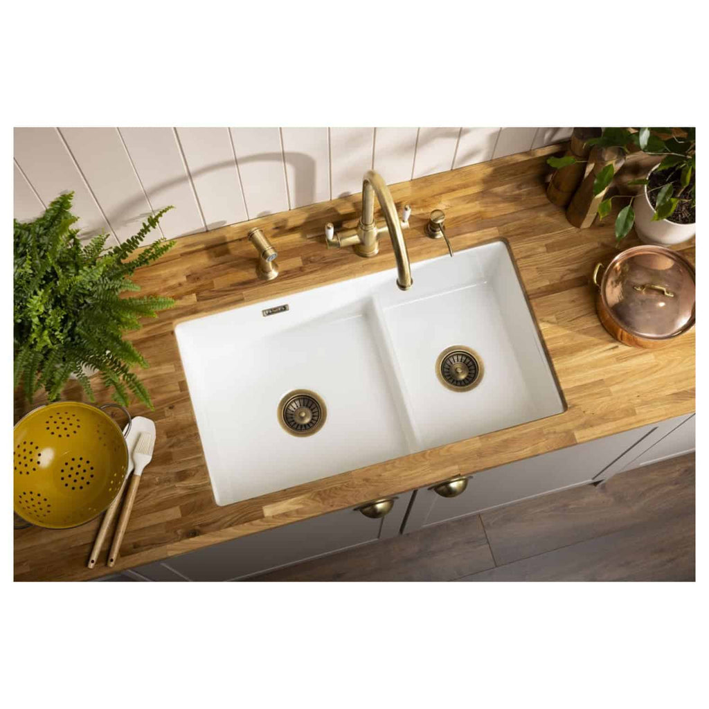 Sustainable farmhouse kitchen sink with brass fixtures and wooden countertop, complemented by fresh greenery and vintage kitchen accessories for a cosy, eco-friendly home aesthetic.