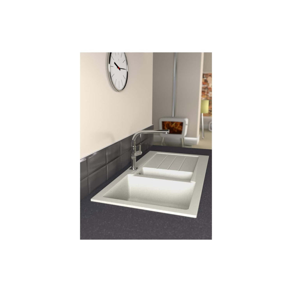 Modern white kitchen sink with integrated drainer and chrome faucet, set on a dark speckled countertop in a contemporary kitchen with black tiled splashback, wall clock, and living area in the background.